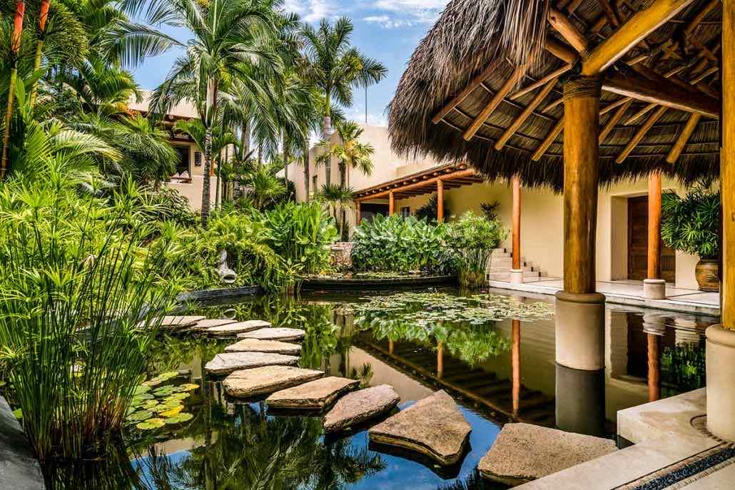 Patio con estanque, piedras de paso y palapa